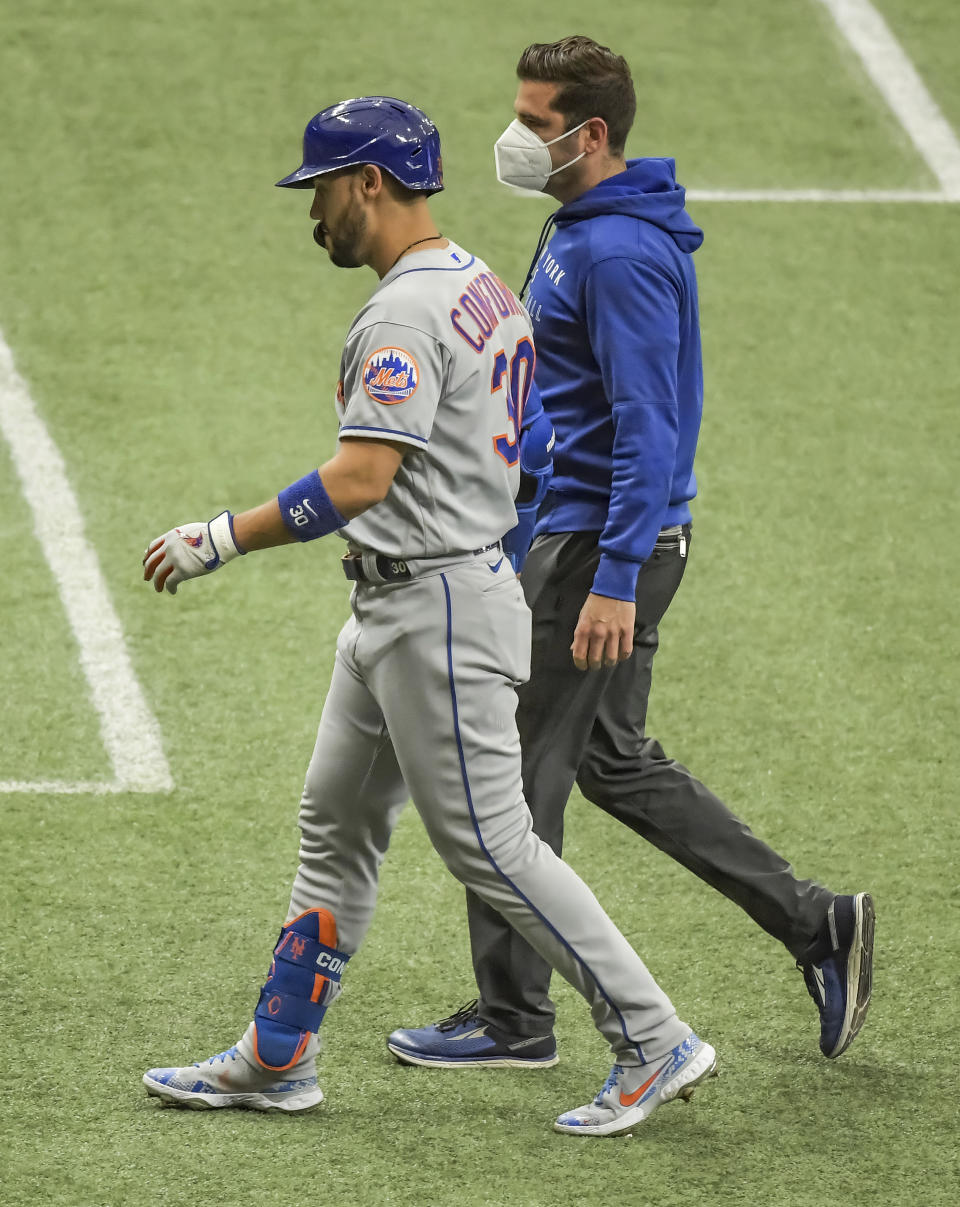 New York Mets' Michael Conforto (30) walks with a trainer as he leaves the field during the first inning of a baseball game against the Tampa Bay Rays, Sunday, May 16, 2021, in St. Petersburg, Fla. (AP Photo/Steve Nesius)