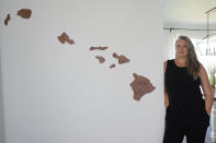 Amy Chadwick, stands by map of Hawaii at her current home Monday, April 8, 2024, in Satellite Beach, Fla. Chadwick, a victim of the fires in Hawaii moved to Florida where she could stretch her homeowners insurance dollars while she waits for her lot to be cleared and for permission to rebuild. (AP Photo/John Raoux)