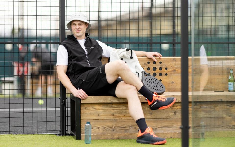 Alex Barton sits on the padel court