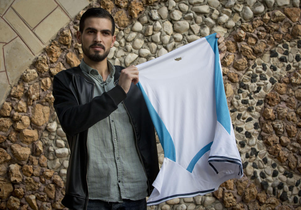 Palestinian Karam Qawasmi, who was shot in the back by Israeli forces in an incident caught on video last year, holds up the shirt he was wearing when he was shot, in the garden of his house, in the West Bank city of Hebron, Sunday, Nov. 10, 2019. In his first interview since the video emerged last week, Karam Qawasmi said he was run over by a military jeep, then beaten for several hours before troops released him, only to shoot him in the back with a painful sponge-tipped bullet as he walked away. (AP Photo/Majdi Mohammed)