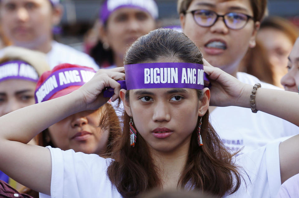 FILE - In this March 8, 2018, file photo, a protester adjusts her headband reading "Frustrate the dictatorship!" during a rally at a Manila square to mark International Women's Day which largely turns out to be an anti-government event in Manila, Philippines. The Philippine president signed Tuesday, July 16, 2019 a bill into law penalizing a range of acts of sexual harassment including catcalling, wolf-whistling and persistent telling of sexual jokes, which pro-women's groups have accused him of committing. (AP Photo/Bullit Marquez, File)