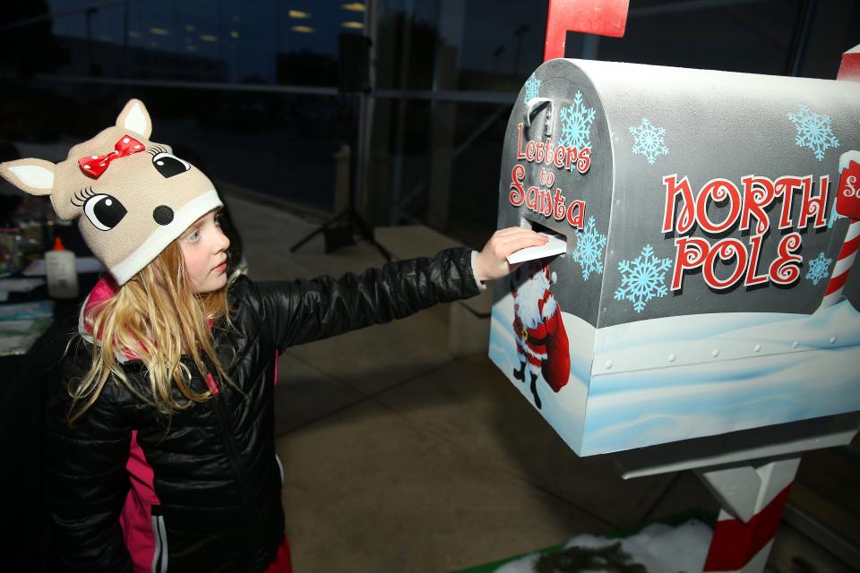 A girl drops a letter to Santa in the special North Pole mailbox before the Christmas tree lighting and grant ceremony at Texas Motor Speedway on Dec. 4, 2018 in Fort Worth, Texas.