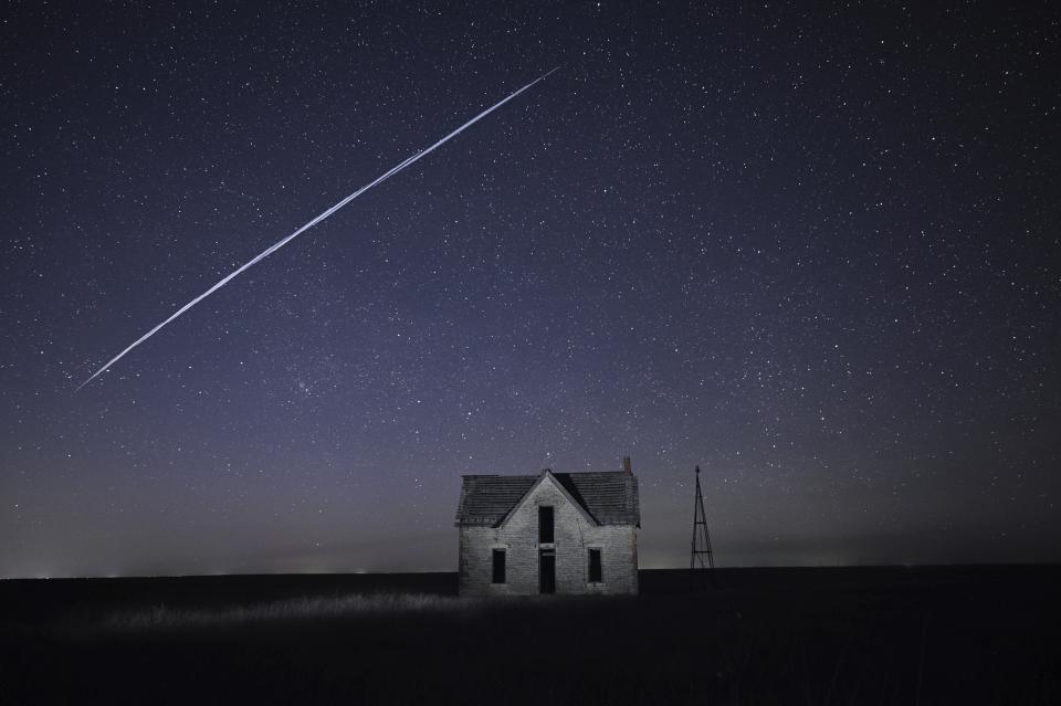 FILE - In this photo taken with a long exposure, a string of Elon Musk's SpaceX StarLink satellites passes over an old stone house near Florence, Kan, May 6, 2021. Musk is helping reconnect Tonga to the internet via the StarLink satellites after a volcanic eruption and tsunami cut off the South Pacific nation more than three weeks ago, according to officials, while repairs on an undersea cable are proving more difficult than first thought. (AP Photo/Reed Hoffmann, File)