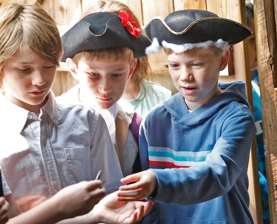 Cohasset third graders Levi Murray, Charles Balck and Thomas Martin, all 8 years old, look over a hand-forged nail during a tour of the Historic Winslow House in Marshfield on May 30, 2023.