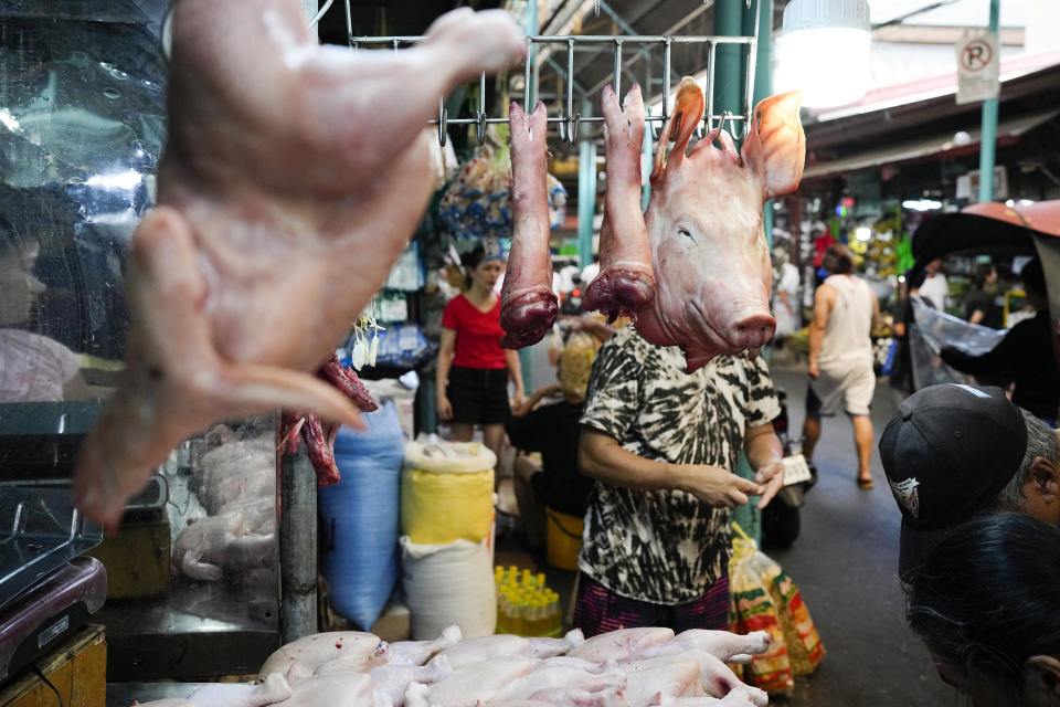 A meat vendor counts money at a public market in Marikina, Philippines on Wednesday, April 24, 2024. (AP Photo/Aaron Favila)