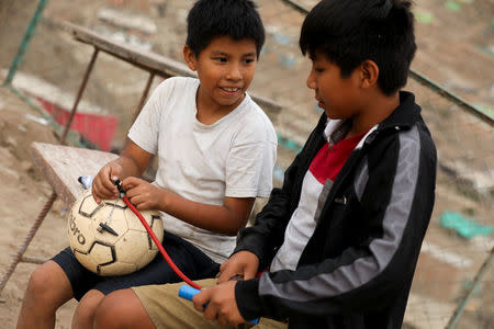 Niños inflan un balón de fútbol en la barriada Nueva Unión en el distrito de Villa María del Triunfo en Lima. 29 de abril de 2018. REUTERS/Mariana Bazo