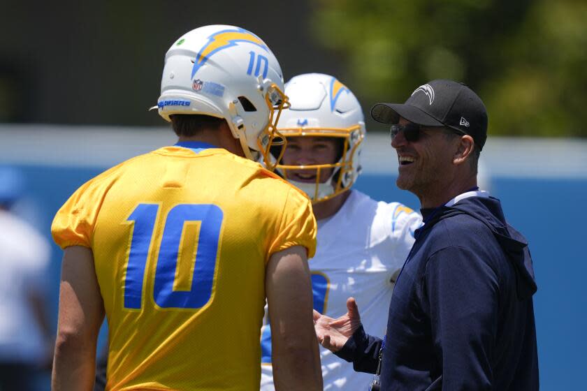 Chargers coach Jim Harbaugh (right) speaks with quarterback Justin Herbert.