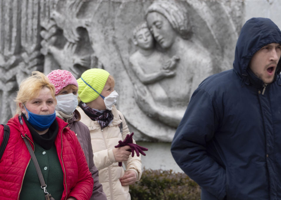 Women wearing face masks to protect against coronavirus walk past a Soviet era bas-relief in St. Petersburg, Russia, Thursday, May 21, 2020. (AP Photo/Dmitri Lovetsky)