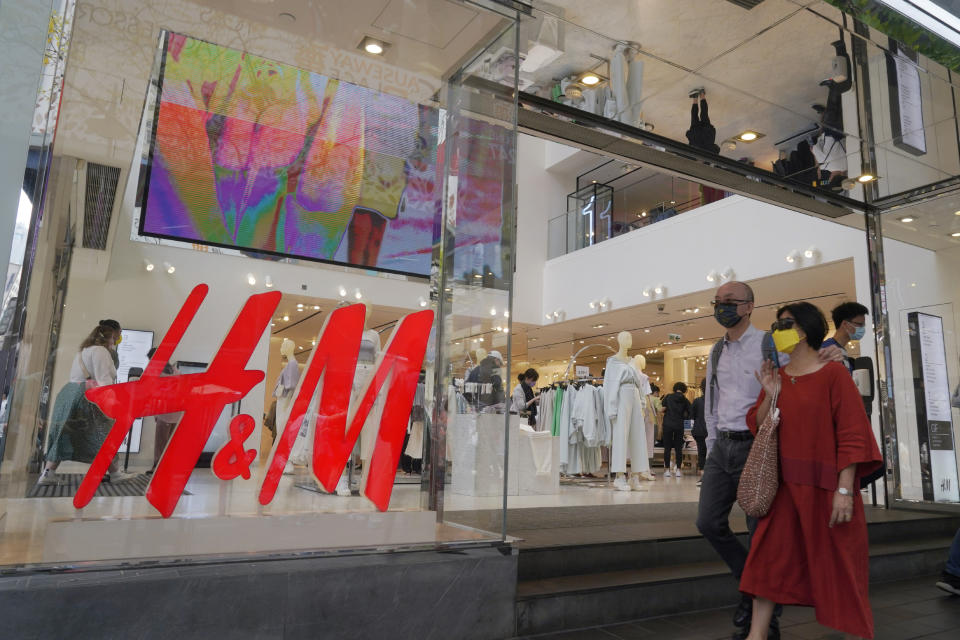 People walk past an H&M clothing store in Hong Kong, Saturday, March 27, 2021. H&M disappeared from the internet in China as the government raised pressure on shoe and clothing brands and announced sanctions Friday, March 26, 2021, against British officials in a spiraling fight over complaints of abuses in the Xinjiang region. (AP Photo/Kin Cheung)