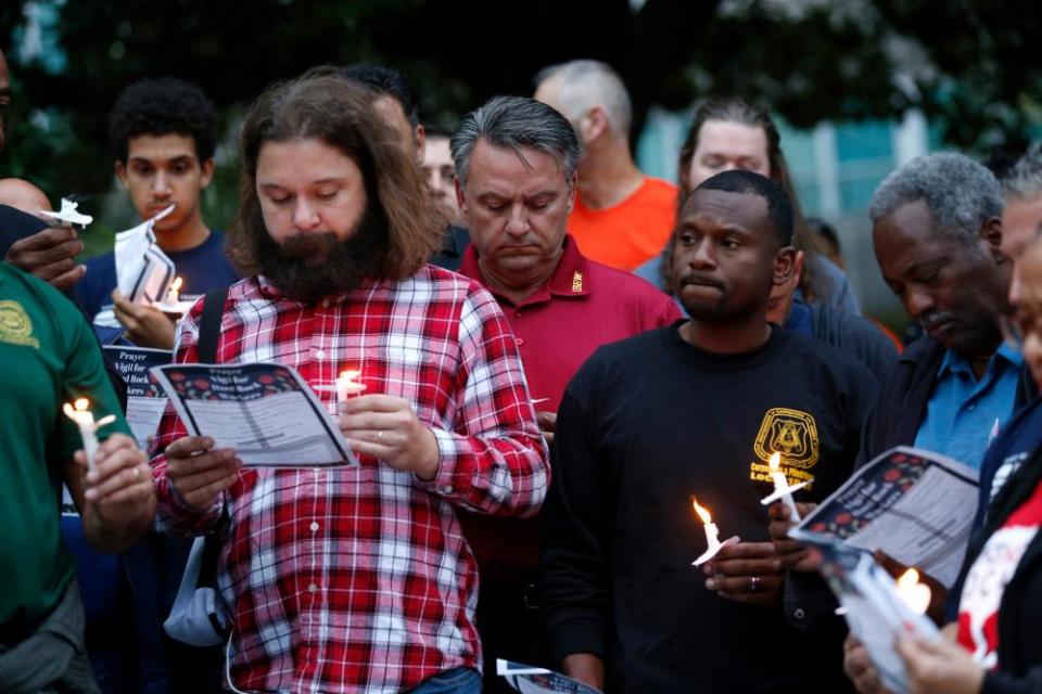 People hold candles during a candlelight vigil outside city hall for deceased and injured workers from the Hard Rock Hotel construction collapse.