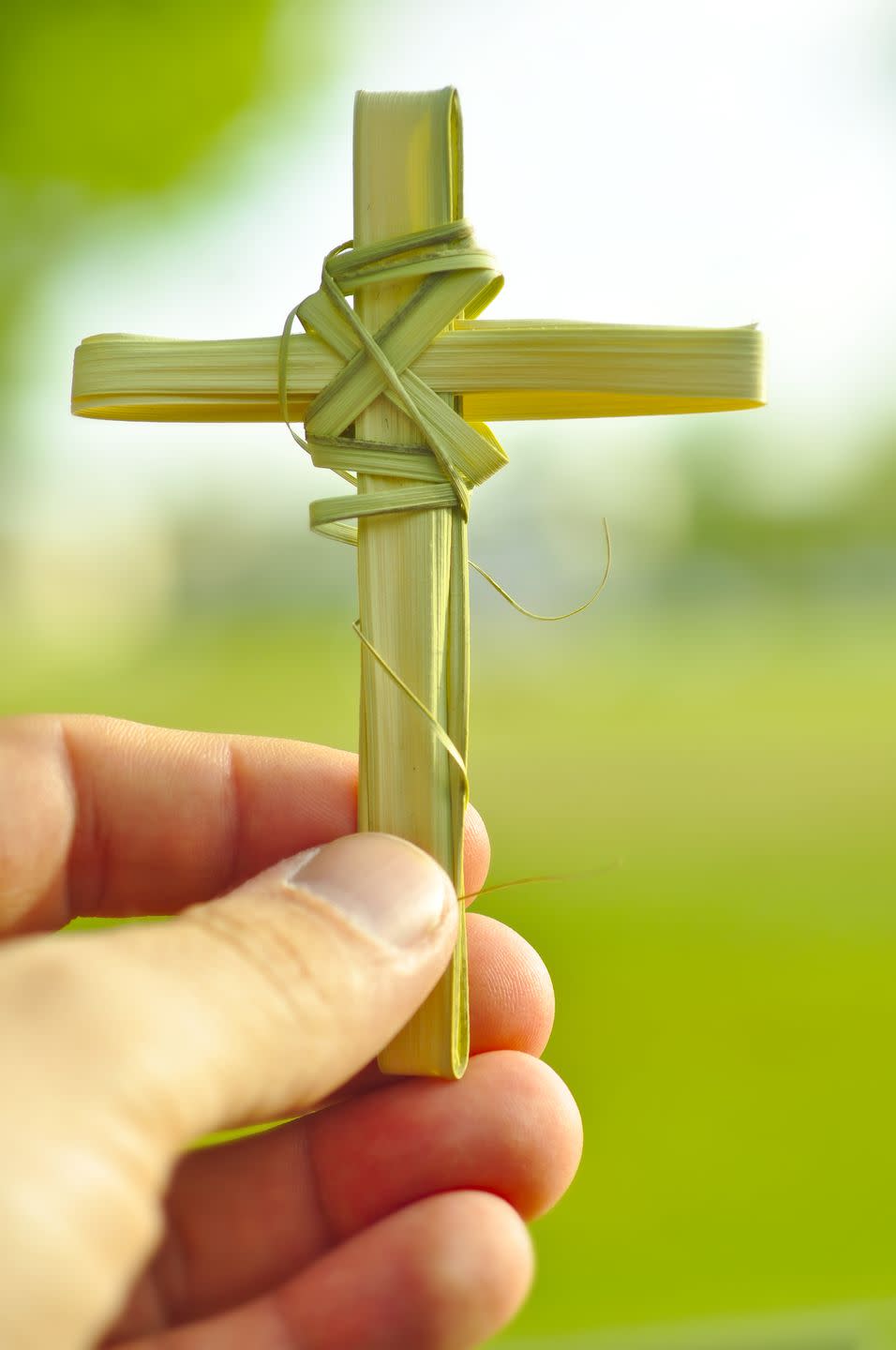 hand holding cross made out of palm fronds