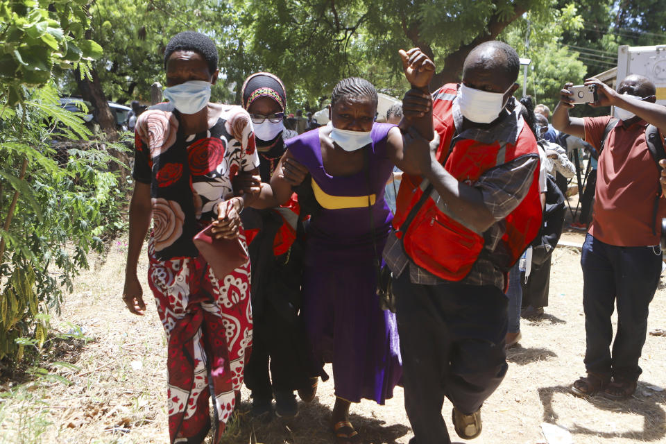 A family member grieves with other relatives as they wait to receive the bodies of victims of a religious cult for burial in Malindi Funeral home in Kilifi, Kenya Tuesday, March. 26, 2024. A family in coastal Kenya has received four bodies of their kin who were victims of a doomsday cult in which 429 bodies were exhumed in a vast ranch occupied by the cult leader. Tuesday marked day one of the handing over of 34 bodies whose DNA matched with that of families who believed their loved ones died in the cult. (AP Photo/Andrew Kasuku)