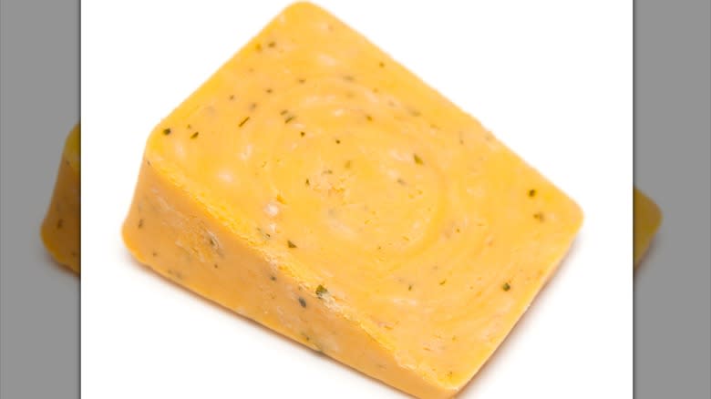 Wedge of double gloucester cheese speckled with herbs