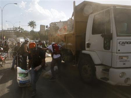 Anti-government protesters carry debris from a truck to build a barricade along a highway during a protest against Nicolas Maduro's government in Caracas March 20, 2014. REUTERS/Marco Bello