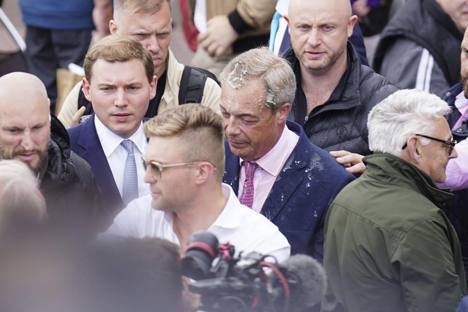 Leader of Reform UK Nigel Farage walks away after a drink was thrown over him when he left the Moon and Starfish pub where he launched his General Election campaign at Clacton-on-Sea, England, Tuesday, June 4, 2024. (James Manning/PA via AP)