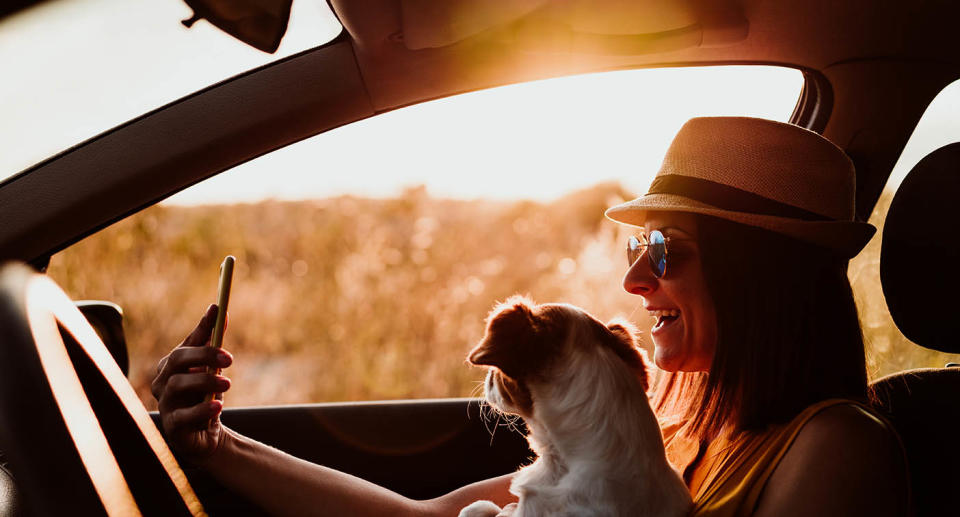 A woman takes a selfie with a dog in a car. Source: Getty Images