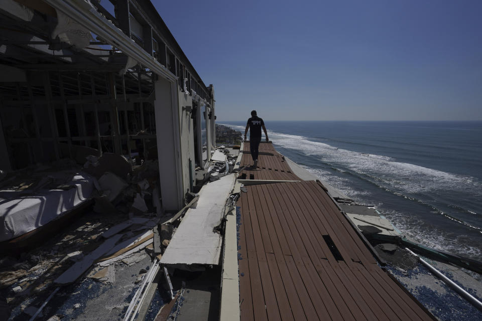 A man walks alongside damaged apartments in the aftermath of Hurricane Otis, in the Diamonds subdivision of Acapulco, Mexico, Thursday, Nov. 9, 2023. Nearly three weeks after the Category 5 hurricane devastated this Pacific port, leaving at least 48 people dead and the city’s infrastructure in tatters, the cleanup continues. (AP Photo/Marco Ugarte)