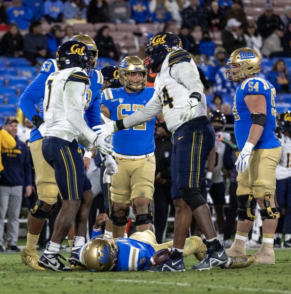 Cal's Xavier Carlton slaps hands with David Reese as Dante Moore lies on the ground.