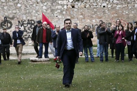 Greece's newly-appointed Prime Minister Alexis Tsipras arrives holding flowers for a ceremony at the Kessariani shooting range site where hundreds of members of the Greek Resistance were executed by Nazi occupation forces during World War II in Athens January 26, 2015. REUTERS/Alkis Konstantinidis