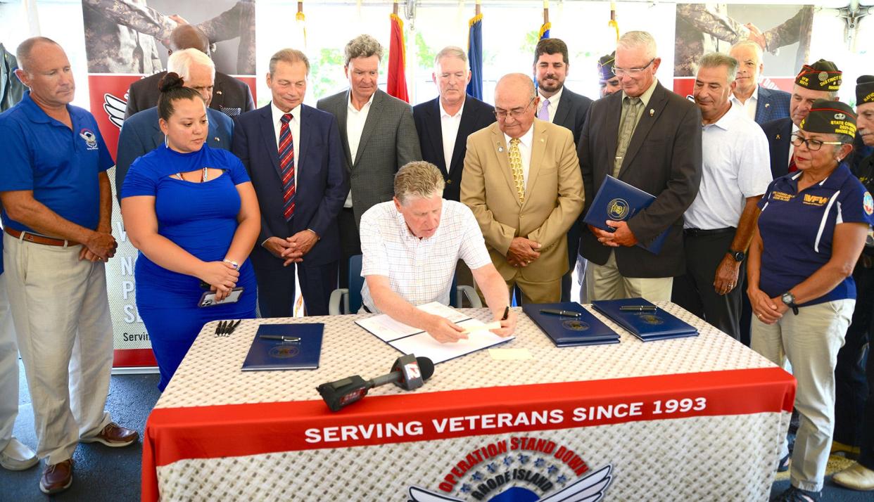 Gov. Dan McKee signs a veterans bill during Operation Stand Down in Johnston on July 21.