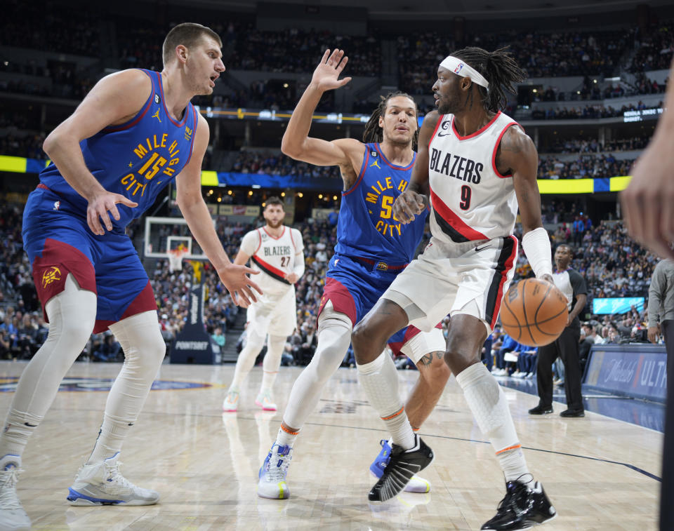 Portland Trail Blazers forward Jerami Grant, front right, is trapped with the ball by Denver Nuggets center Nikola Jokic, left, and forward Aaron Gordon in the first half of an NBA basketball game Friday, Dec. 23, 2022, in Denver. (AP Photo/David Zalubowski)