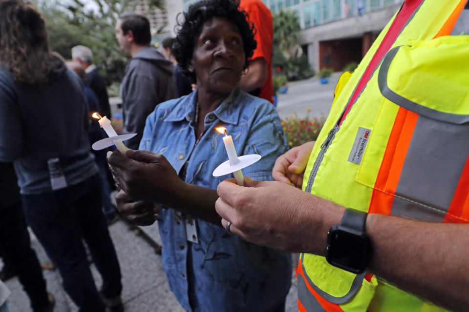 People hold candles during a candlelight vigil outside city hall for deceased and injured workers from the Hard Rock Hotel construction collapse Sat., Oct., 12, in New Orleans, on Thursday, Oct. 17, 2019. The vigil was organized by various area labor groups. (AP Photo/Gerald Herbert)