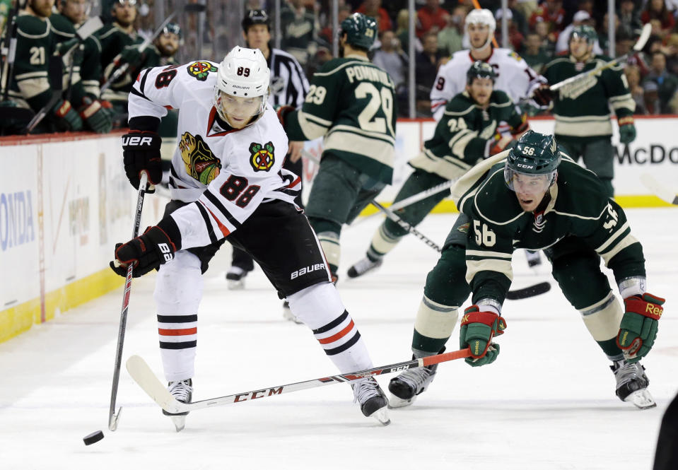 Chicago Blackhawks right wing Patrick Kane (88) and Minnesota Wild left wing Erik Haula (56), of Finland, chase the puck during the second period of Game 6 of an NHL hockey second-round playoff series in St. Paul, Minn., Tuesday, May 13, 2014. (AP Photo/Ann Heisenfelt)