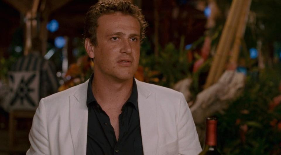 Jason Segel in a casual button-up shirt and blazer, sitting at an outdoor restaurant