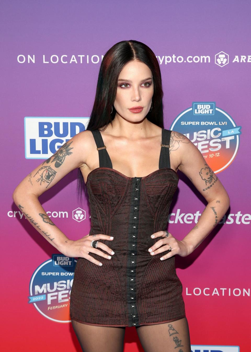 Halsey poses with her hands on her hips at a Super Bowl event red carpet