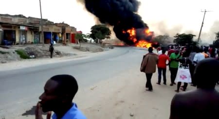 People look towards a fire following a fuel truck collision in Rubirizi