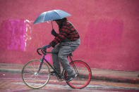 A man attempts to stay dry while riding along Colorado Boulevard in Pasadena, Calif., during a rainstorm, Monday, Oct. 25, 2021. (Sarah Reingewirtz/The Orange County Register via AP)