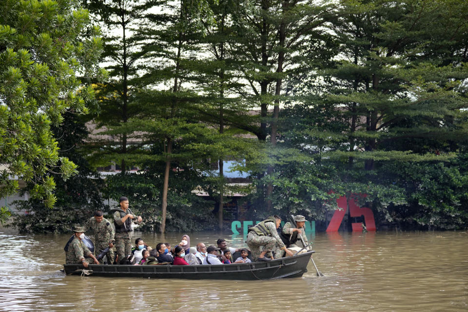 Rescuers and solders evacuate villagers on a boat on a flood-hit road in Shah Alam, on the outskirts of Kuala Lumpur, Malaysia, Monday, Dec. 20, 2021. Rescue services on Monday worked to free thousands of people trapped by Malaysia's worst flooding in years after heavy rains stopped following more than three days of torrential downpours in the capital and around the country. (AP Photo/Vincent Thian)