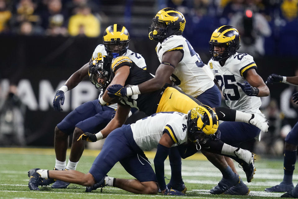 Iowa running back Gavin Williams, center, is tackled by Michigan linebacker David Ojabo, right, and defensive back Vincent Gray (4) during the first half of the Big Ten championship NCAA college football game, Saturday, Dec. 4, 2021, in Indianapolis. (AP Photo/Darron Cummings)