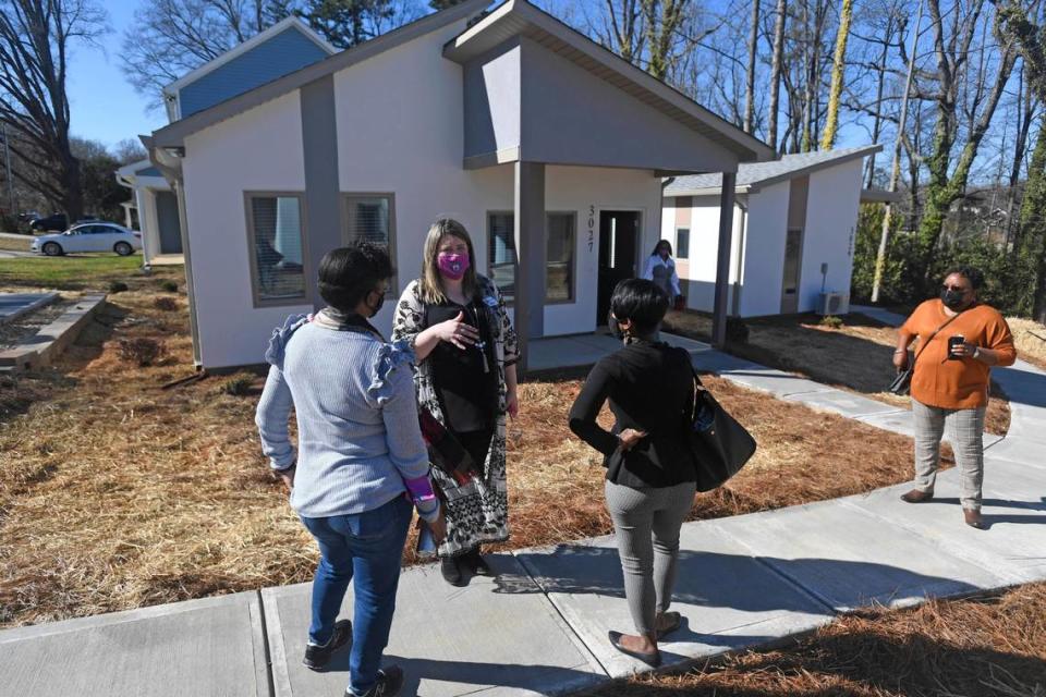 Rachel Cody, Director of Marketing for Home Again Foundation, center, talks about the cottages during the opening of the new affordable housing community, launched by the nonprofit in Charlotte on Wednesday, February 24, 2021. The group has built 8 single family units with energy efficient affordable units with goals of expansion with further fundraising. The program will have additional services to help people improve their financial stability.