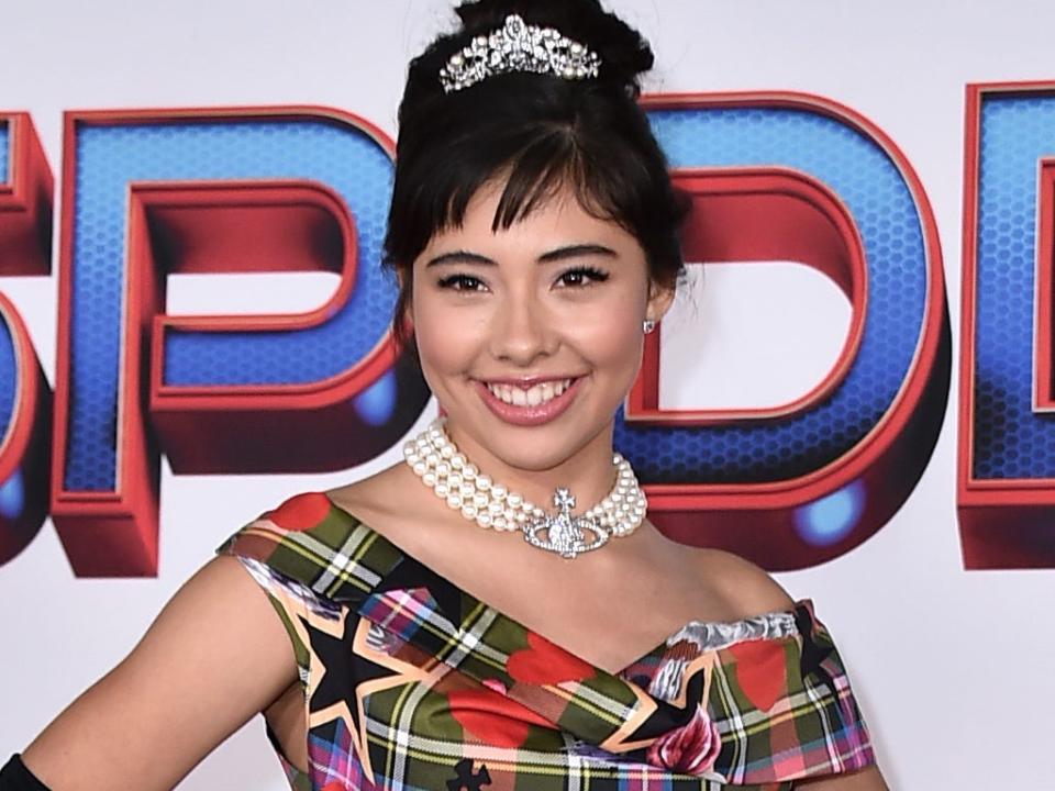 Xochitl Gomez wears a colorful dress, black gloves, and tiara at the red carpet premiere of "Spider-Man: No Way Home" in December 2021.