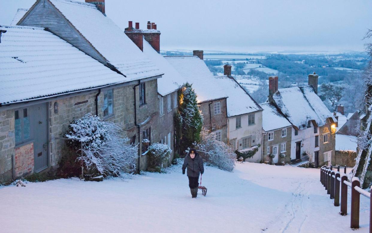 Kieron Taylor pulls his sled up the snow covered Gold Hill at Shaftesbury in Dorset at dawn - Graham Hunt/BNPS