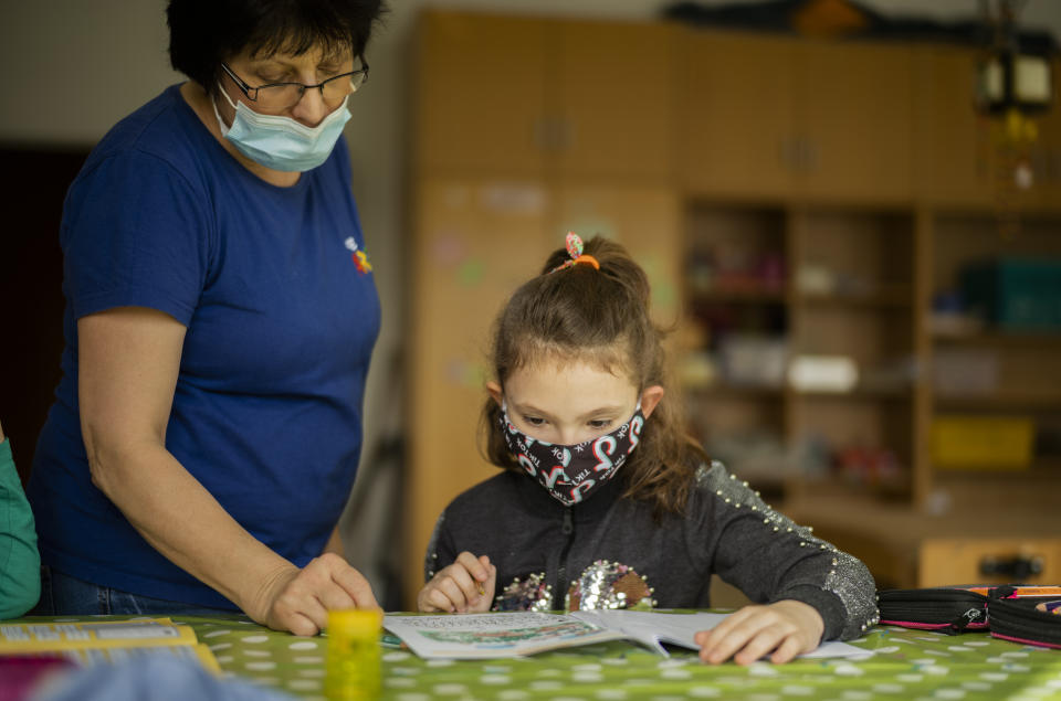 Nine-year-old girl Pauline receives assistance for her schoolwork by a social worker at the Arche, or Ark, an organization that supports children, youth and families in the Hellersdorf neighbourhood, on the eastern outskirts of Berlin, Germany, Tuesday, Feb. 23, 2021. Since the outbreak of the coronavirus pandemic, the Arche has had to reduce their real face-to-face assistance or traditional classroom schooling as an offer for children, mainly from underprivileged families, drastically. Some kids are still allowed to come over in person, but only once every two weeks. (AP Photo/Markus Schreiber)