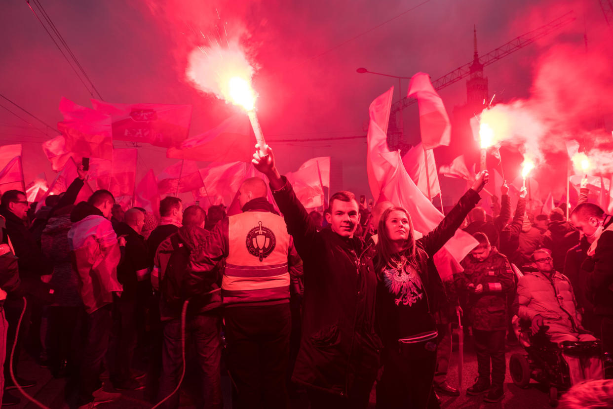 A couple holds flares as thousands gather for the annual march for Poland's Independence Day. The annual event marks the restoration of the country's&nbsp;sovereignty and is celebrated on Nov. 11. (Photo: SOPA Images via Getty Images)