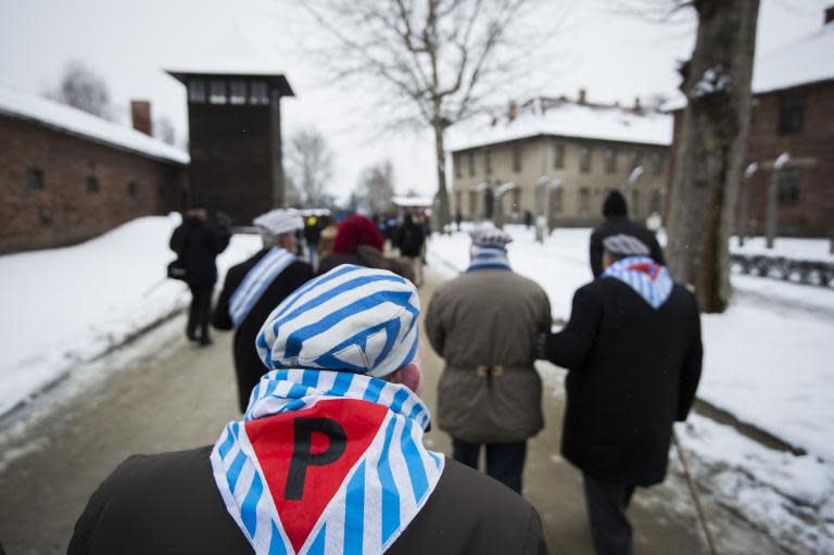 Survivors walk past a watch tower after paying tribute to fallen comrades at the "death wall" execution spot in the former Auschwitz concentration camp