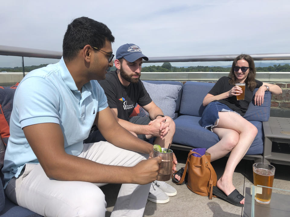 In this June 26, 2019 photo, Ashish Bibireddy, 23, Floyd Kenney, 27, and Kyrra Engle speak at the rooftop bar at The Bristol Hotel in Bristol, Va. Ten medical students were on a tour of the city organized by a medical school with the aim of luring them to practice in rural communities facing health care shortages after graduation. (AP Photo/Sudhin Thanawala)
