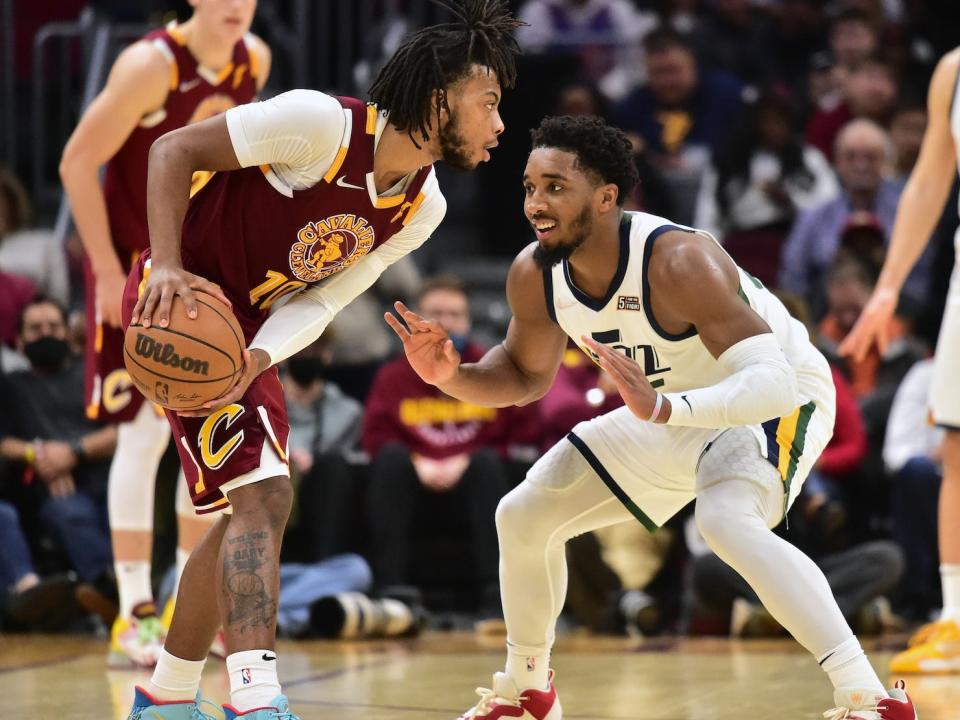 Darius Garland holds the ball while Donovan Mitchell smiles and guards him in a 2022 game.