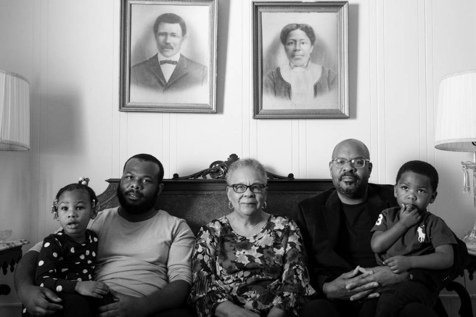 Toney and Nellie Strayhorn, both freed from slavery, purchased a small plot of land on the outskirts of Chapel Hill in Carrboro, NC, named after white supremacist Julian Carr, in the mid 1870s. They built a one-room cabin that eventually expanded to a two-story home. The family survived and thrived through the racial violent times of Reconstruction and Jim Crow. Dolores Clark (centered) sits with her children and great-grandchildren in the home her great-grandparents, Toney and Nellie Strayhorn (pictured on the wall), built around 1879 in Carrboro, North Carolina.