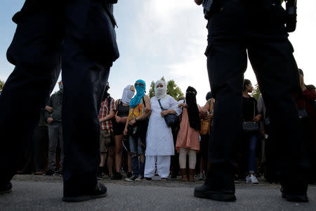 Police stand guard as masked protesters surround the Bellahoj police station as they participate in a demonstration against the Danish face veil ban in Copenhagen, Denmark, August 1, 2018. REUTERS/Andrew Kelly