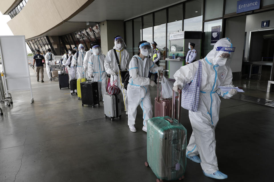 Foreign passengers wearing protective suits walk for their flight to China at Manila's International Airport, Philippines, Monday, Jan. 18, 2021. Coronavirus infections in the Philippines have surged past 500,000 in a new bleak milestone with the government facing criticisms for failing to immediately launch a vaccination program amid a global scramble for COVID-19 vaccines. (AP Photo/Aaron Favila)