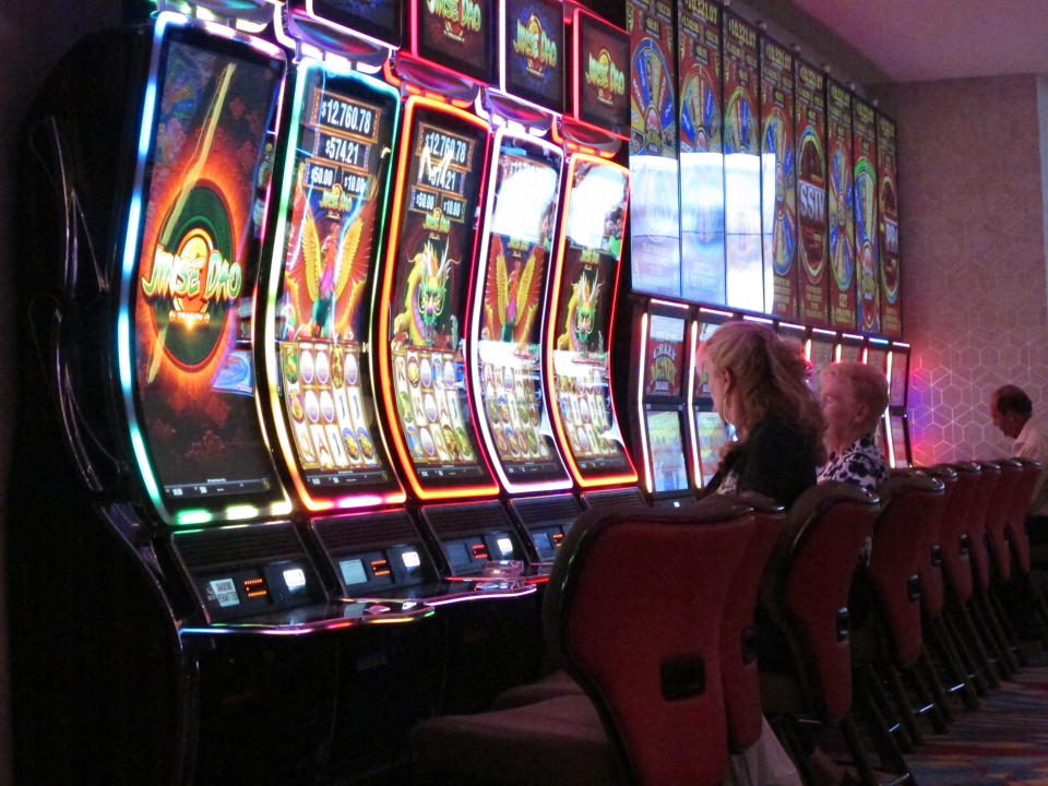 This June 20, 2019 photo shows gamblers playing slot machines at the Hard Rock casino in Atlantic City N.J. As of March 16, 2020, casinos in at least 15 states had shut down due to the coronavirus, including Atlantic City's nine casinos which were due to close at 8 p.m. (AP Photo/Wayne Parry)