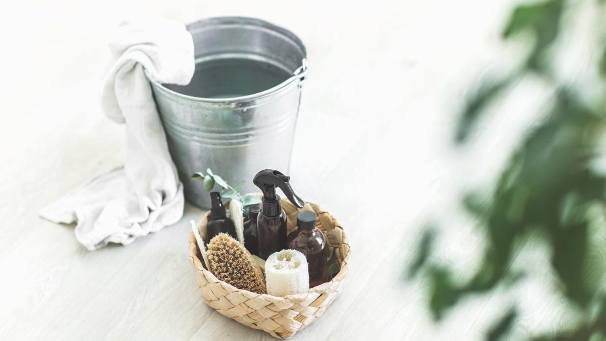  Cleaning products on the floor in front of a metal bucket 