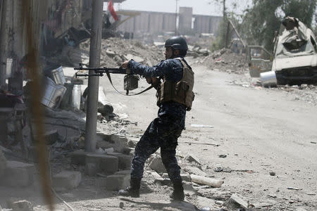 A member of the Iraqi Federal Police fires against Islamic State positions at the frontline in western Mosul. REUTERS/Alkis Konstantinidis