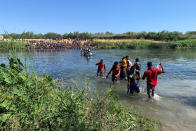 Migrants find an alternate place to cross from Mexico to the United States after access to a dam was closed, Sunday, Sept. 19, 2021, in Ciudad Acuña, Mexico. U.S. officials said that within the next few days, they plan to ramp up expulsion flights for some of the thousands of Haitian migrants who have gathered in the Texas city from across the border in Mexico. (AP Photo/Sarah Blake Morgan)