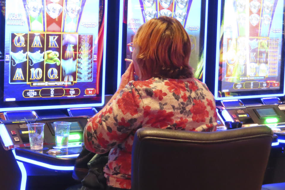 A gambler smokes while playing a slot machine at the Ocean Casino Resort in Atlantic City N.J. on Nov. 29, 2023. On Tuesday, Dec. 12, casino workers pushing for a smoking ban at the city's nine casinos publicized a letter from Shawn Fain, international president of the United Auto Workers union, calling on New Jersey lawmakers to ban smoking in the casinos. (AP Photo/Wayne Parry)