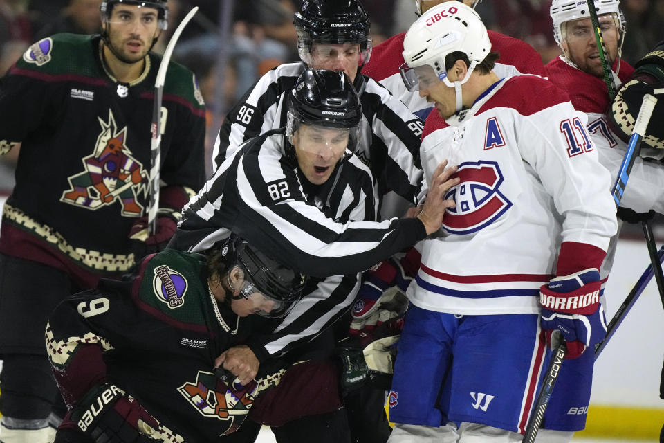 Linesman Ryan Galloway (82) separates Arizona Coyotes right wing Clayton Keller (9) and Montreal Canadiens right wing Brendan Gallagher (11) during the third period of an NHL hockey game Thursday, Nov. 2, 2023, in Tempe, Ariz. (AP Photo/Ross D. Franklin)
